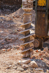 Heavy construction drill auger with soil and rocks attached used for foundation drilling at building site