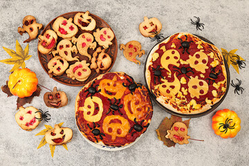 Halloween food concept, holiday meal idea for kids and adults. Scary pizzas and cookies in the form of monsters and ghosts on an old concrete background, cafe and menu advertising,