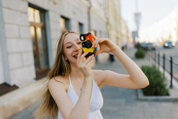 Young Woman Holding a Camera on a City Street During Daylight