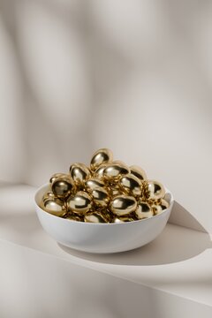 White bowl filled with shiny gold eggs in soft light