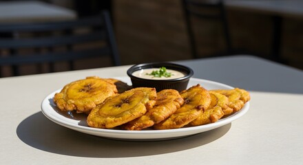 A plate of golden patacones served with a creamy dipping sauce garnished with green onions on top