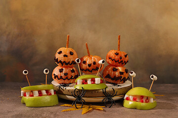 Scary monsters and ghosts made of apples and tangerines on old concrete background, cafe and menu advertising, restaurant business card, Halloween food concept, holiday meal idea for kids and adults.