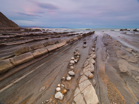 Layered rock formations on a Spanish coast - A long exposure shot of the striking flysch rock formations on the Basque coastline, with the gentle blur of the rising tide.