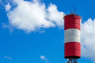 Lighthouse stands tall against a vibrant blue sky with fluffy white clouds during daytime