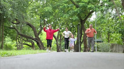 Asian family jogging together in the park. Parents, child, and grandfather exercising outdoors, promoting healthy lifestyle and family bonding