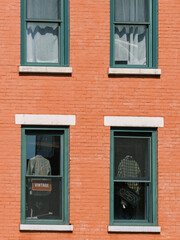 Fototapeta premium Vintage clothing displayed in windows of a red brick building in a bustling urban area