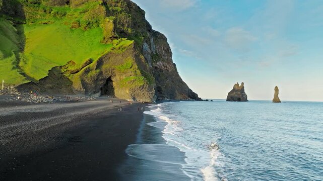 Drone aerial footage of Reynisfjara black sand beach Iceland. Volcanic coastline with sea stacks and ocean waves captured in cinematic 4K ProRes quality..