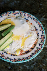 Deliciously prepared fried eggs served with fresh cucumber slices on a decorative plate