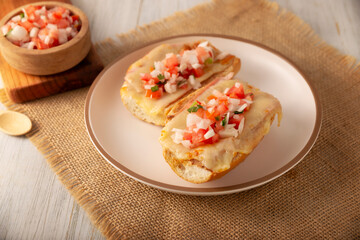 Molletes. Mexican recipe based on bolillo bread split lengthwise, spread with refried beans and gratin cheese, adding pico de gallo sauce and some protein such as ham, bacon or chorizo.