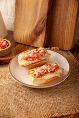 Molletes. Mexican recipe based on bolillo bread split lengthwise, spread with refried beans and gratin cheese, adding pico de gallo sauce and some protein such as ham, bacon or chorizo.