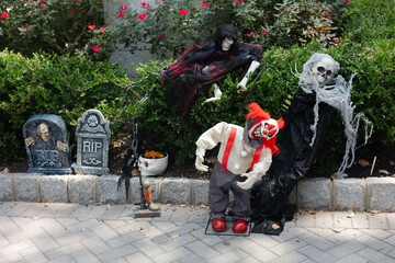Halloween decorations featuring spooky figures near a garden during daylight hours