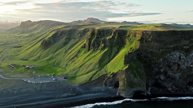 Volcanic cliffs and black sand coast Reynisfjara Iceland aerial. Cinematic 4K drone footage shows dramatic Atlantic waves hitting shoreline.