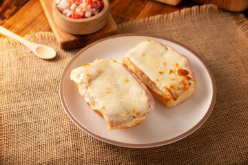 Molletes. Mexican recipe based on bolillo bread split lengthwise, spread with refried beans and gratin cheese, adding pico de gallo sauce and some protein such as ham, bacon or chorizo.