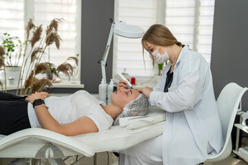 beautician doing  cosmetic procedure with ultrasound skin tightening for rejuvenation woman face
