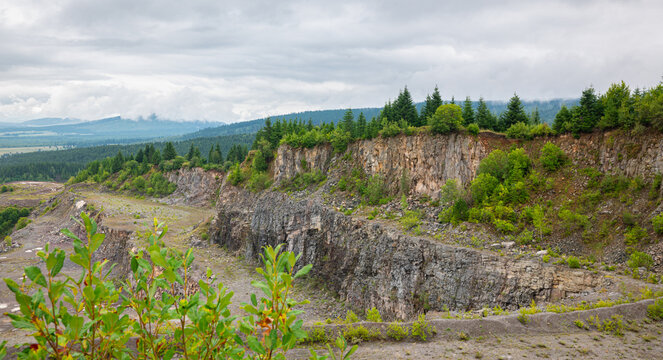 Picturesque view of wooded cliffs and quarries in a lush green landscape overlooking the Ciuc Valley in the Eastern Carpathians, Romania.