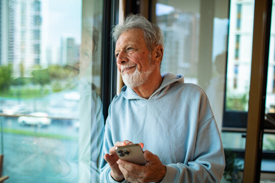 Senior Man Using Smartphone by Window
