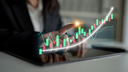 A business professional interacts with digital charts on a tablet, showcasing financial analysis...