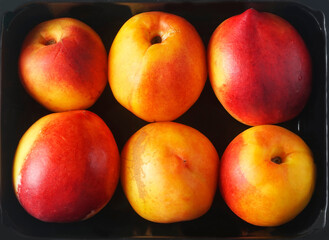 ripe nectarines in a black plastic container