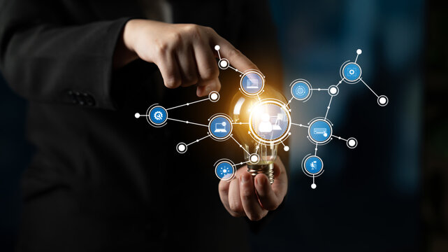 A businessman points at a glowing light bulb icon surrounded by data connections, symbolizing innovation and technology in the corporate world. Perfect for showcasing modern ideas. Tessel