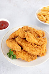 Fried chicken strips with French fries and ketchup on white background. Fast food