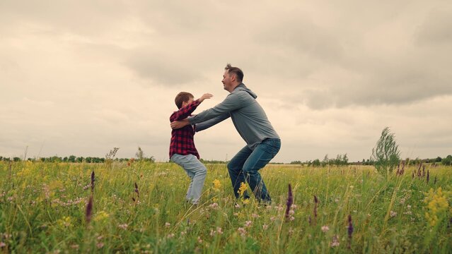 Father lifts and spins son in flowers, joy of family togetherness, child dreams of flying, superhero roleplay with dad, outdoor happiness and laughter, meaningful parental bond, wildflower meadow