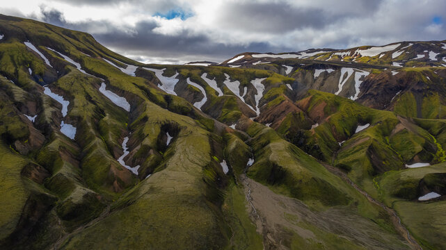 Rhyolite mountains in Iceland seen from above with snow and moss streaks across steep volcanic ridges