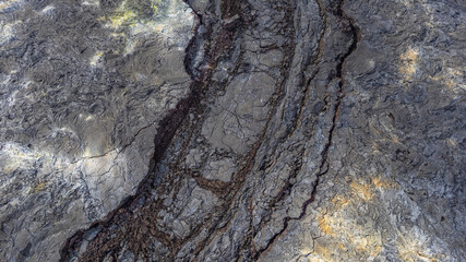 Close up aerial view of rough volcanic lava field in Iceland showing cracks textures and patterns of cooled dark rock formations