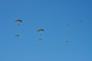 Parachute drop of several uniformed soldiers