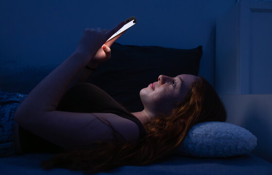 Woman using smartphone in bed at night