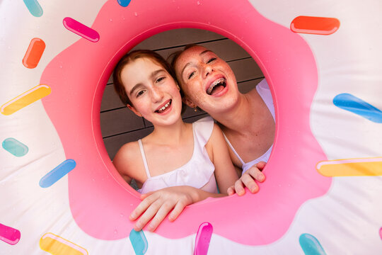 Happy sisters enjoying summer with donut float
