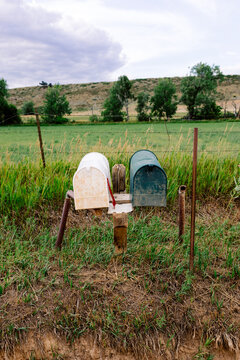A pair of mailboxes attached to wooden supports along a rural road 
