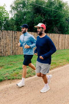 Full body shot of two men jogging along a dirt trail in Boulder