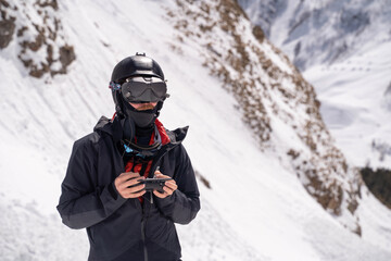 FPV pilot with controller in snowy mountains