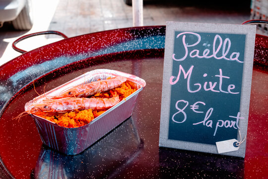 mixed paella in a takeaway tray with a price sign beside it