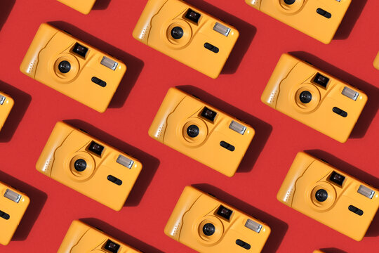 Bright Orange Film Cameras making pattern on Red Background 