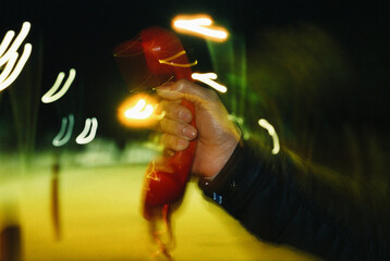 man lifts a red phone outdoors at night, shutter drag, 35mm