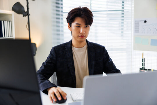 Young professional working at a desk with computers.