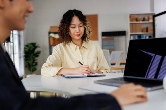 Woman taking notes during a meeting with a colleague.