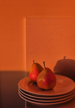 Fresh pears on plates with warm orange backdrop at sunset