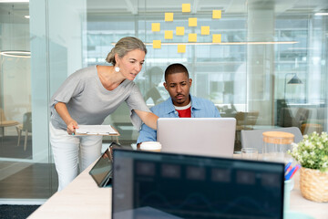 Managers working together in modern office using laptop and documents