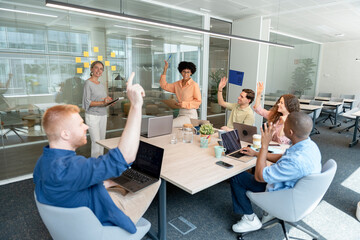 Multicultural team raising hands during brainstorming session