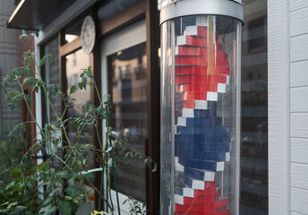 Barber pole outside shop near  plants