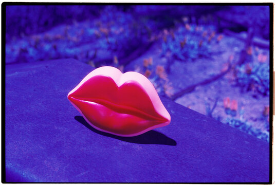 red lips on stone against a surreal violet landscape, 35mm