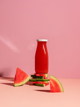 Vibrant watermelon juice in a bottle with fresh slices