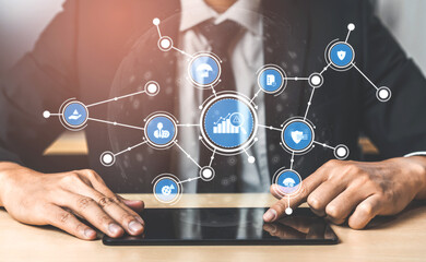 A businessman interacts with a digital tablet, surrounded by icons illustrating business analytics and technology trends, showcasing modern corporate strategies and innovation. Tessel