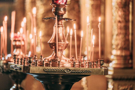 Candles lit in a bronze holder during evening prayer at a temple