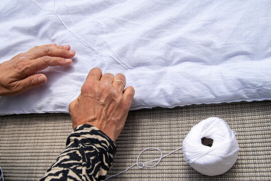 A woman is sewing a quilt with a needle and thread.
