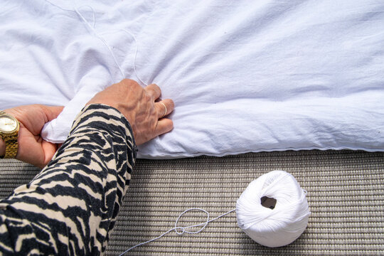 A woman is sewing a quilt with a needle and thread.