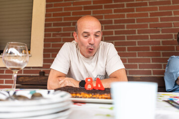 Mature man blowing out candles on birthday cake celebrating