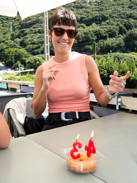 Woman celebrating 34th birthday with donut and candles